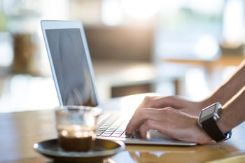 Man using a laptop while having cup of coffee in cafe