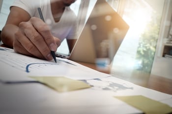 business documents on office table with smart phone and digital tablet and graph business diagram and man working in the background